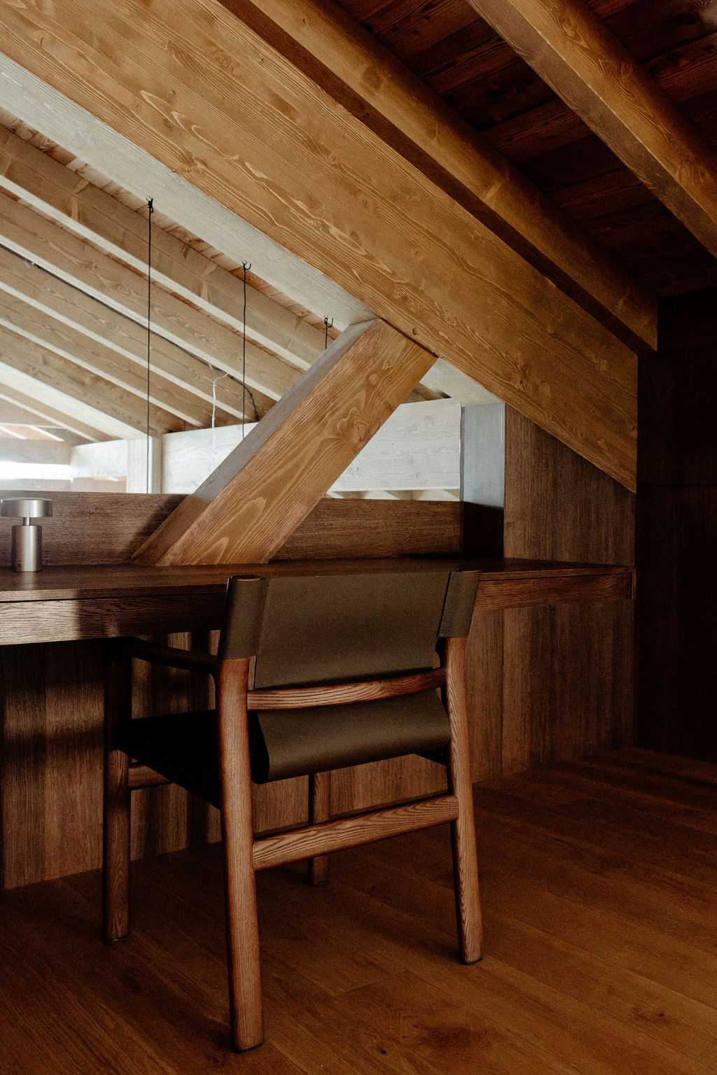Bureau en bois sous la charpente apparente avec chaise en cuir noir